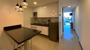 A modern kitchen with a black countertop, stainless steel appliances, and pendant lighting. - Buena Vista Rental House (Santa Cruz)