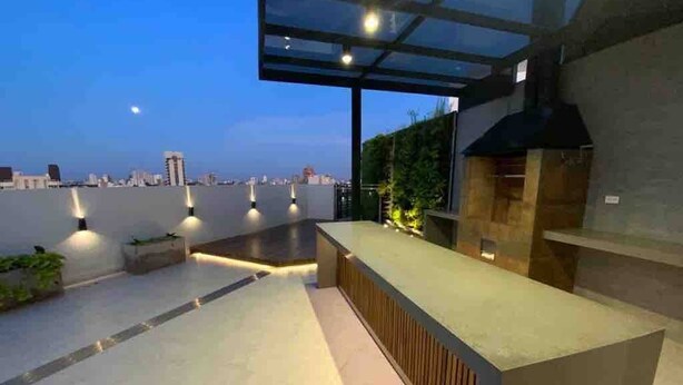 A rooftop terrace with a glass enclosure, a built-in grill, and city views. - Buena Vista Rental House (Santa Cruz)