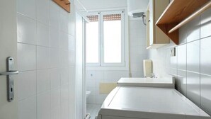 Un baño moderno con baldosas blancas, un mueble de tocador de madera, un espejo y una ventana.