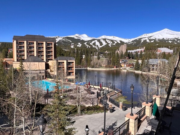 A hotel with a pool, outdoor seating, and a view of snow-capped mountains.