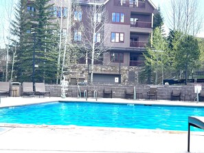 A swimming pool with lounge chairs and a stone wall.