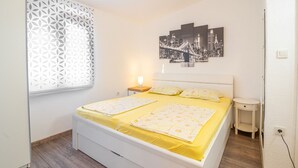 Una camera da letto con un letto, un comodino, un quadro appeso al muro e una finestra con persiana decorata.