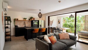 Une cuisine moderne dotée d’un îlot central, un coin repas avec une table et des chaises, et un espace de détente avec un canapé et des coussins.