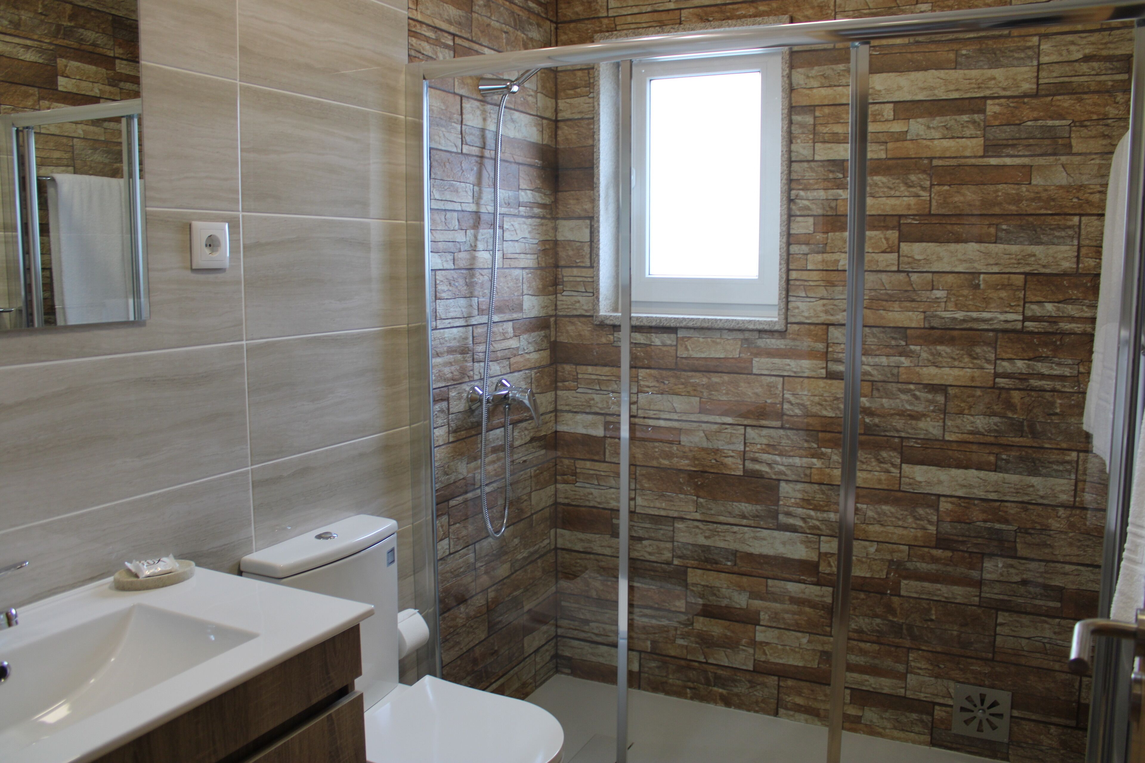 A modern bathroom with a glass-enclosed shower, a toilet, and a sink.