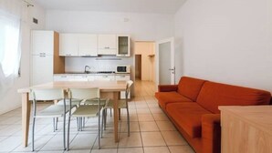 A compact living space with a kitchen, dining area, and a sofa. - VILLA TERESA 02 (Lido di Jesolo)