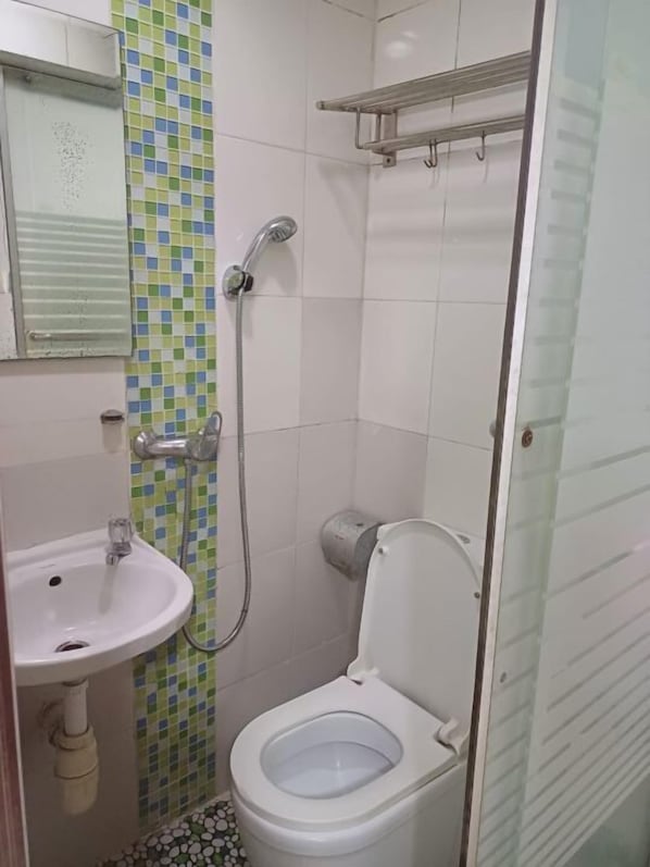 Un baño pequeño con inodoro, lavamanos y ducha.