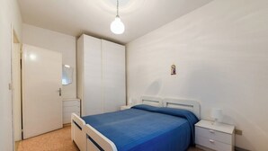 A bedroom with a bed, bedside tables, a wardrobe, and a hanging light fixture. - VILLA TERESA 19 (Lido di Jesolo)