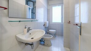 A bathroom with a white sink, toilet, and a glass shelf above the sink. - VILLA TERESA 19 (Lido di Jesolo)