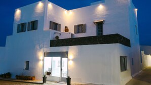A modern white building with multiple windows and a balcony. - Seven Grapes - Karterados (Santorini)