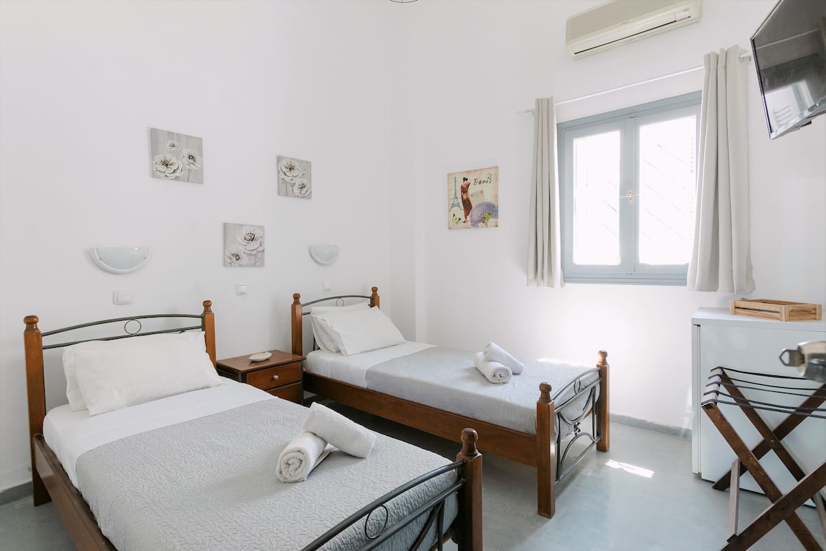 Une chambre d’hôtel avec deux lits, un bureau et une fenêtre avec des rideaux.