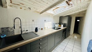 A modern kitchen with a large island, dark cabinets, and a skylight.