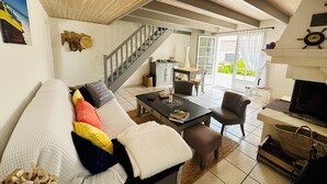 A living room with a sofa, coffee table, and TV. There's a staircase leading to another room.
