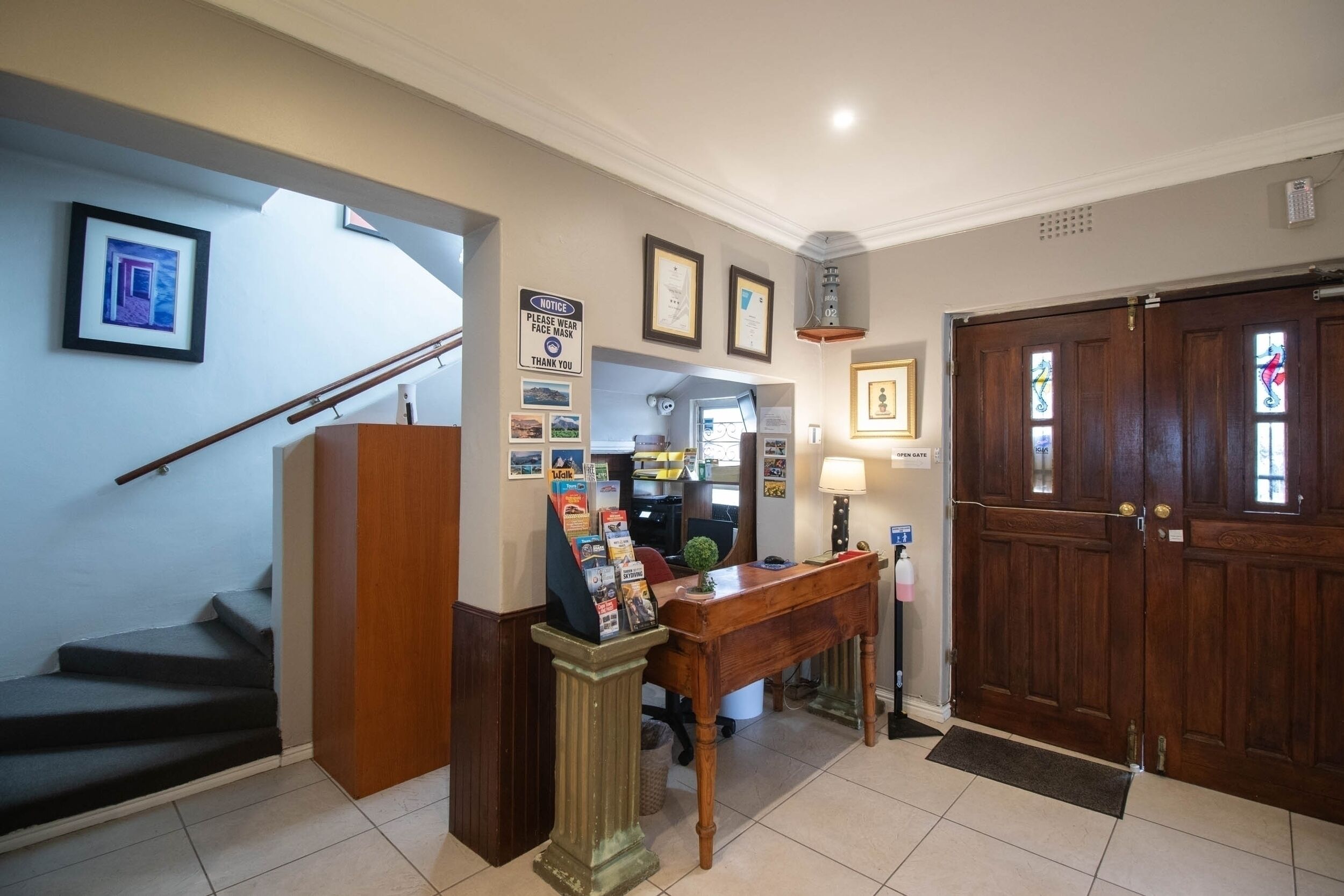 A reception area with a desk, framed certificates, a notice board, and a staircase.