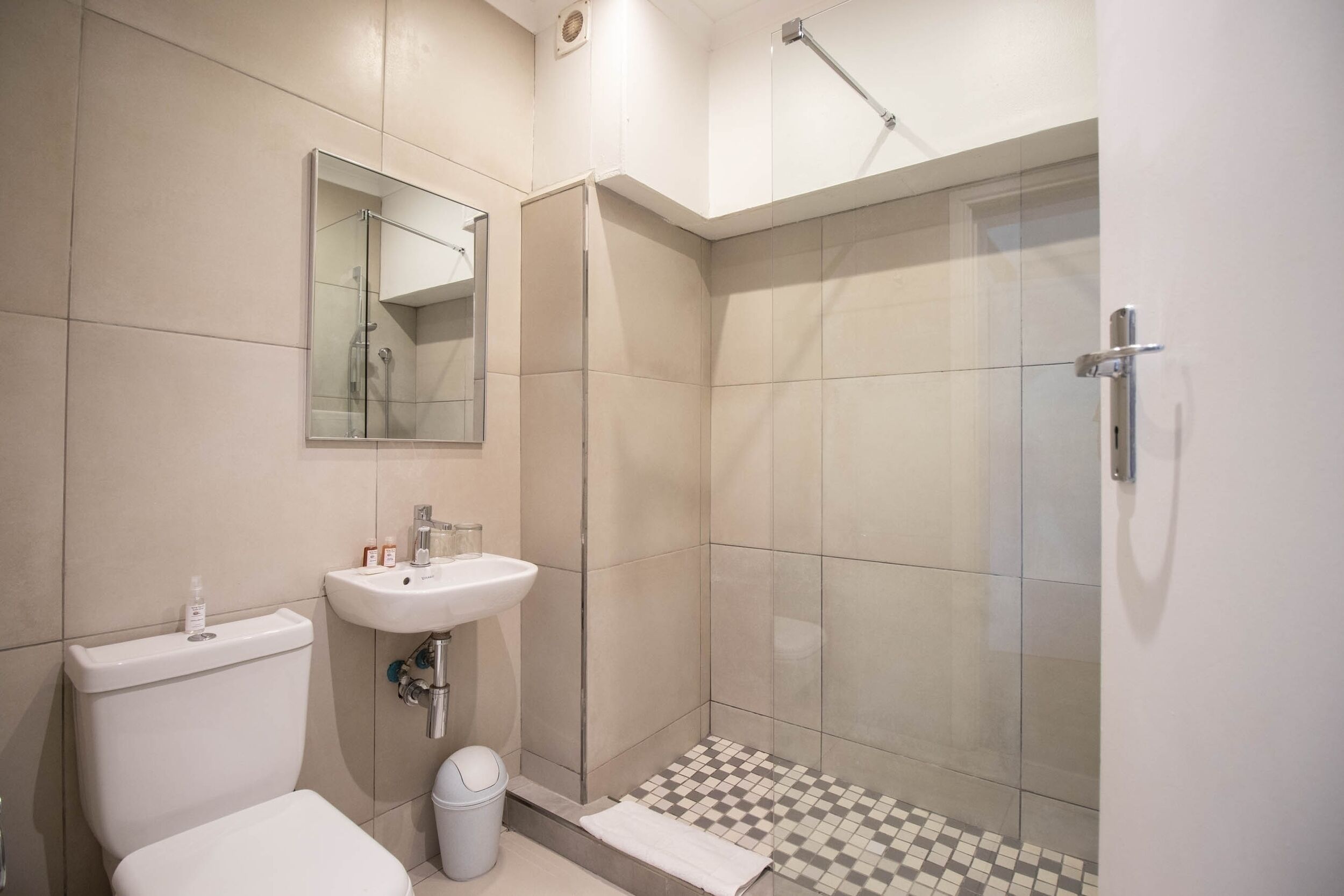 A modern bathroom with a toilet, sink, and glass shower enclosure.