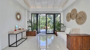 Un hall espacioso y moderno con piso pulido, una consola de madera, un sofá y decoración en las paredes.