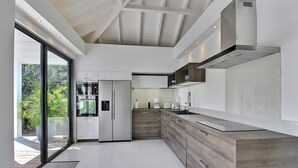 Una cocina moderna con una isla grande, electrodomésticos integrados y vistas al exterior.