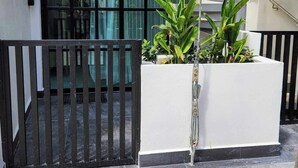 Un bâtiment moderne à l’extérieur blanc, doté d’un portail en métal noir et d’un escalier menant à un étage supérieur.