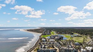 An aerial view of a coastal resort with beachfront properties, a golf course, and a large body of water. - Spectacular Ocean Front Bedroom Views - 626 Newhaven (Fripp Island)