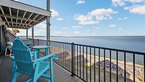 A wooden deck with a view of the water, a covered area with chairs, and a railing. - Spectacular Ocean Front Bedroom Views - 626 Newhaven (Fripp Island)