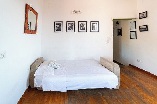 Un dormitorio con una cama individual, un espejo y varias fotografías enmarcadas en la pared.