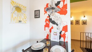 A dining area with a table set for two, a wall with artwork, and a staircase in the background. - Panoramic Penthouse in Naples by Wonderful Italy (Naples)