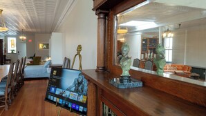 A lobby with a wooden reception desk, a television screen displaying content, and a mirror reflecting the room. - Spacious Condo: Historic Boutique Rental in Downtown Edgerton (Edgerton)