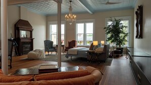 A spacious living room with a large bed, a fireplace, and a chandelier. - Spacious Condo: Historic Boutique Rental in Downtown Edgerton (Edgerton)