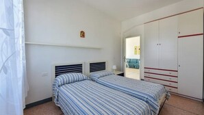 Een slaapkamer met twee bedden, een kledingkast en een klein nachtkastje.