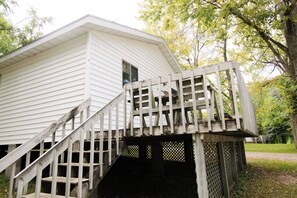 A white building with a wooden staircase leading to a deck.