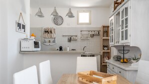 A modern kitchen with white cabinets, a wooden dining table, and pendant lights. - Villetta Emanuela by Wonderful Italy (Syracuse)