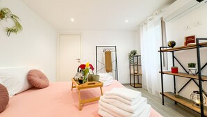 Una habitación de hotel moderna con una cama, una mesita de madera, un estante con plantas y una puerta.