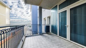 Ein Balkon mit Fliesenboden, Metallgeländer und Glastüren.