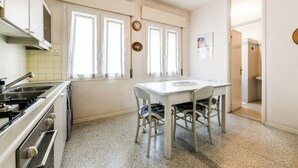 Eine Küche mit Esstisch, Stühlen, Herd und einem Fenster mit Vorhängen.