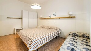 Ein Schlafzimmer mit Bett, Nachttisch, Kleiderschrank und einem Regal mit einer Lampe.