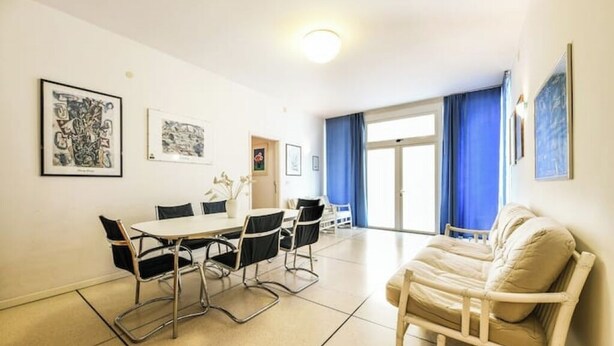 Ein Zimmer mit Esstisch und Stühlen, einer Couch und Kunstwerken an den Wänden.