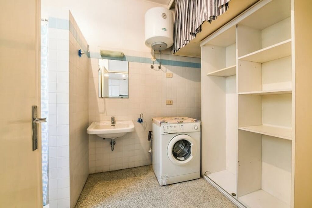 A compact bathroom with a washing machine, a sink, and a towel rack.