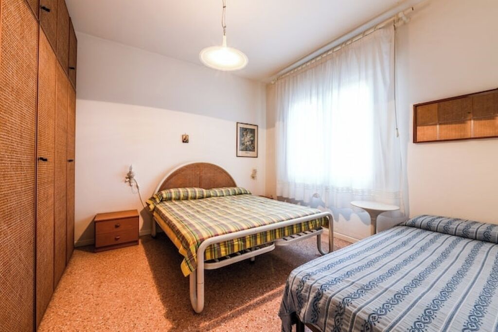A bedroom with a bed, a bedside table, a small table, and a wardrobe.