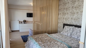 Une chambre à coucher avec un lit, une commode, un globe terrestre et un téléviseur fixé au mur.
