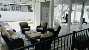 A covered outdoor seating area with wicker furniture and a view of the pool area. - SEA BISCUIT-2024 LUXURY Cherry Grove Home, 4bd/3bth, Private Pool, VERY CLEAN (North Myrtle Beach)