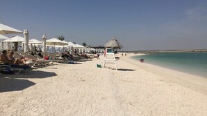 Ein Strand mit Liegestühlen und Sonnenschirmen, einem Rettungsturm und freiem Blick auf das Meer.