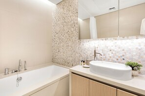 A modern bathroom with a freestanding bathtub, a sink with a mirror above it, and a decorative wall with a hexagonal pattern. - Silkhaus Mayan 5 - Yas Island (Abu Dhabi)