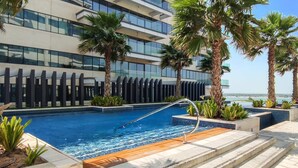Ein modernes Hotel mit Swimmingpool, Palmen und Blick auf den Ozean.