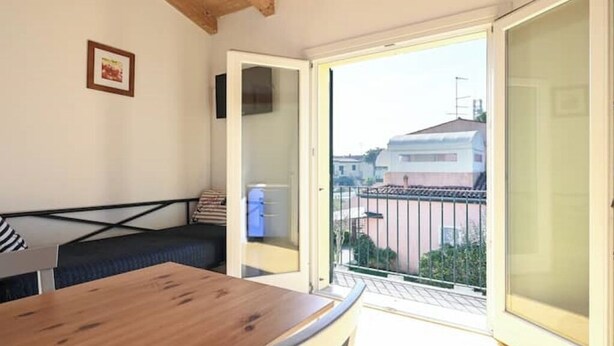 Una habitación con una mesa de madera, un sofá y un balcón con vistas a edificios.