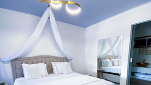A large bed with a canopy, a bench, and a modern light fixture.