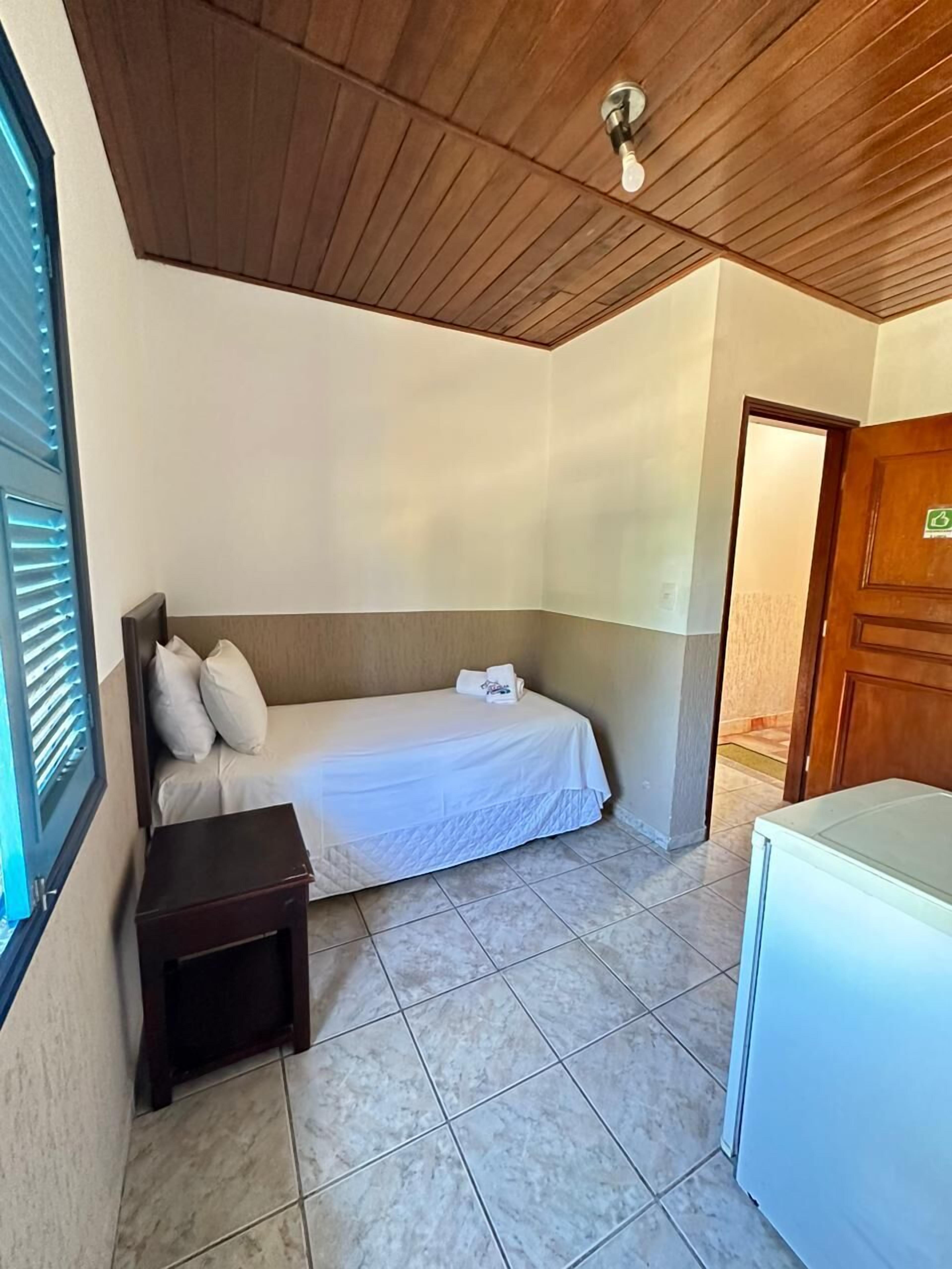 A small, clean room with a bed, bedside table, and a small desk.