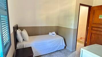 A small, clean room with a bed, bedside table, and a small desk.