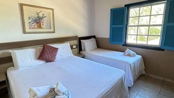 A hotel room with two beds, a wooden ceiling, a window with blue shutters, and a painting on the wall.