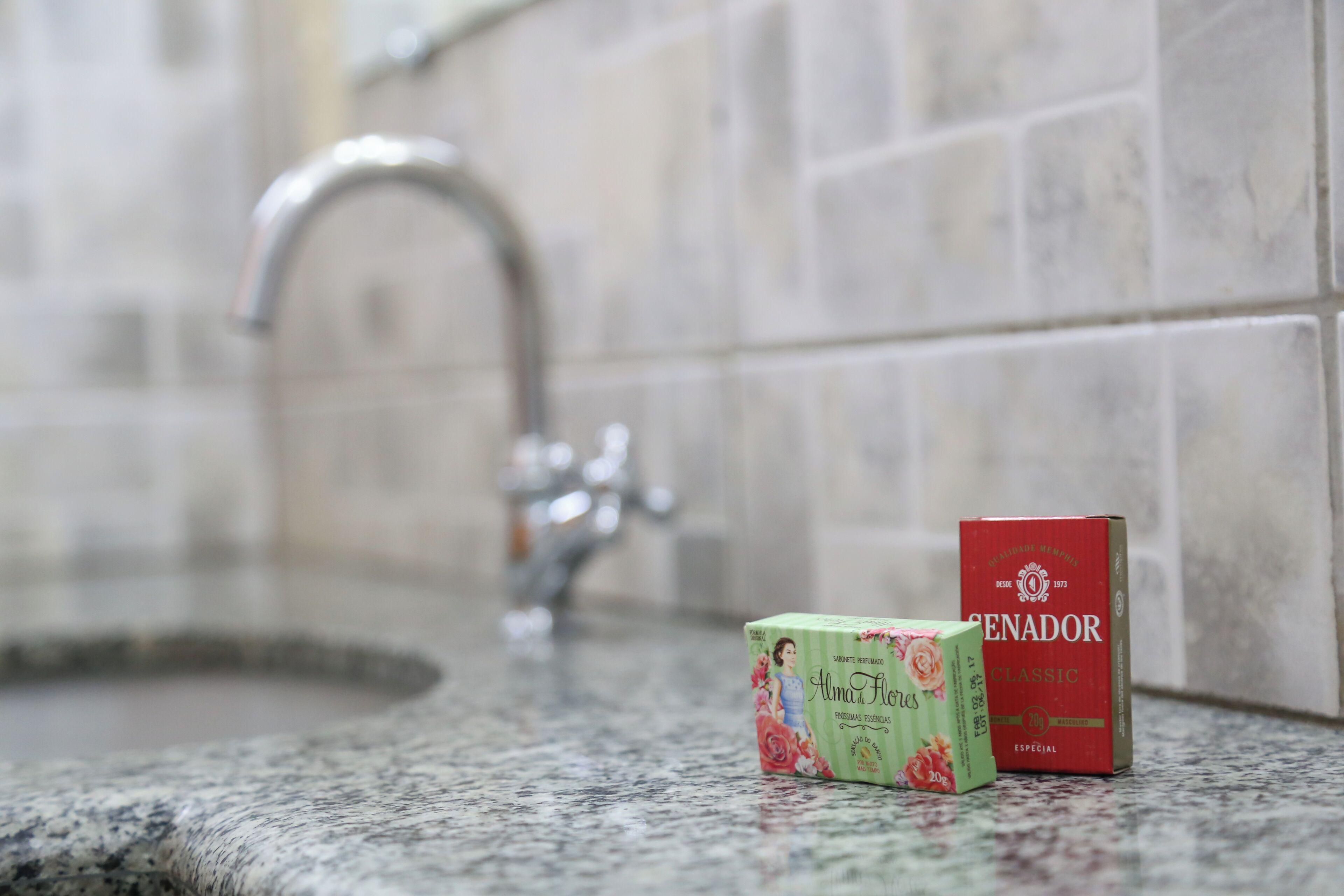 A bathroom with a granite countertop, a faucet, and two boxes of soap.