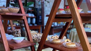 A wooden display stand with various baked goods, including bread and pastries, arranged on multiple tiers.