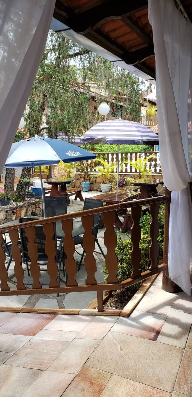 An outdoor patio area with a wooden railing, outdoor seating, and umbrellas.